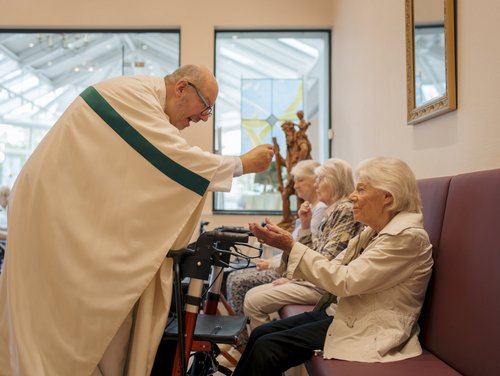 Ein Pfarrer gibt einer Frau ein Leib Christi in die Hand 