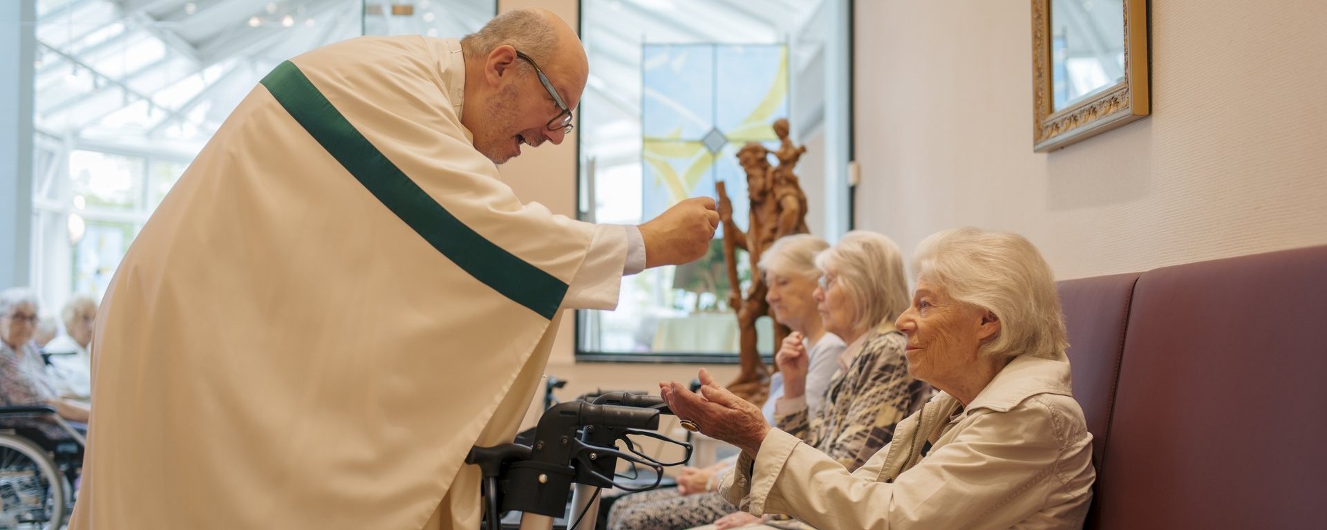 Ein Pfarrer gibt einer Frau ein Leib Christi in die Hand 