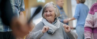 eine Frau im Rollstuhl sieht glücklich in die Kamera und hat Spass 